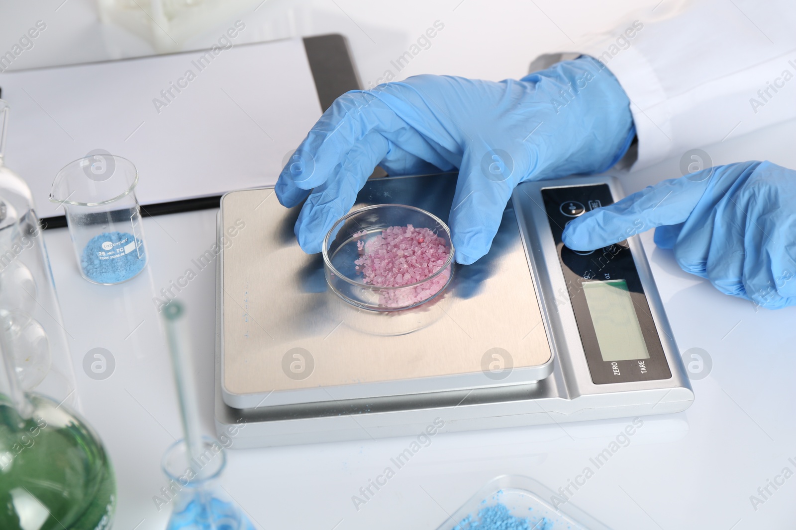 Scientist weighing sample on scales at white table, closeup Photo of Scientist weighing sample on scales at white table, closeup