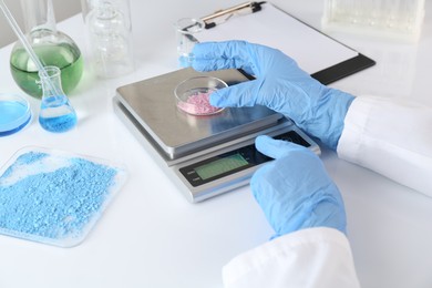 Photo of Scientist weighing sample on scales at white table, closeup