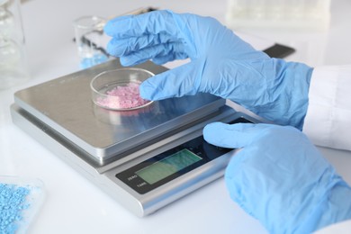 Photo of Scientist weighing sample on scales at white table, closeup