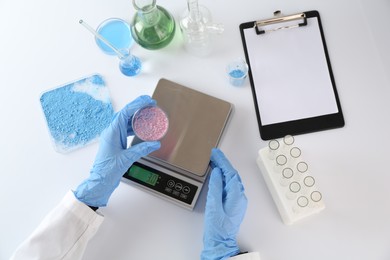 Photo of Scientist working with Petri dish of sample and scales at white table, top view