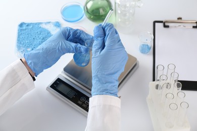 Photo of Scientist working with sample and scales at white table, closeup