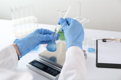 Photo of Scientist working with sample and scales at white table, closeup