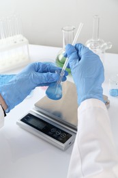 Photo of Scientist working with sample and scales at white table, closeup