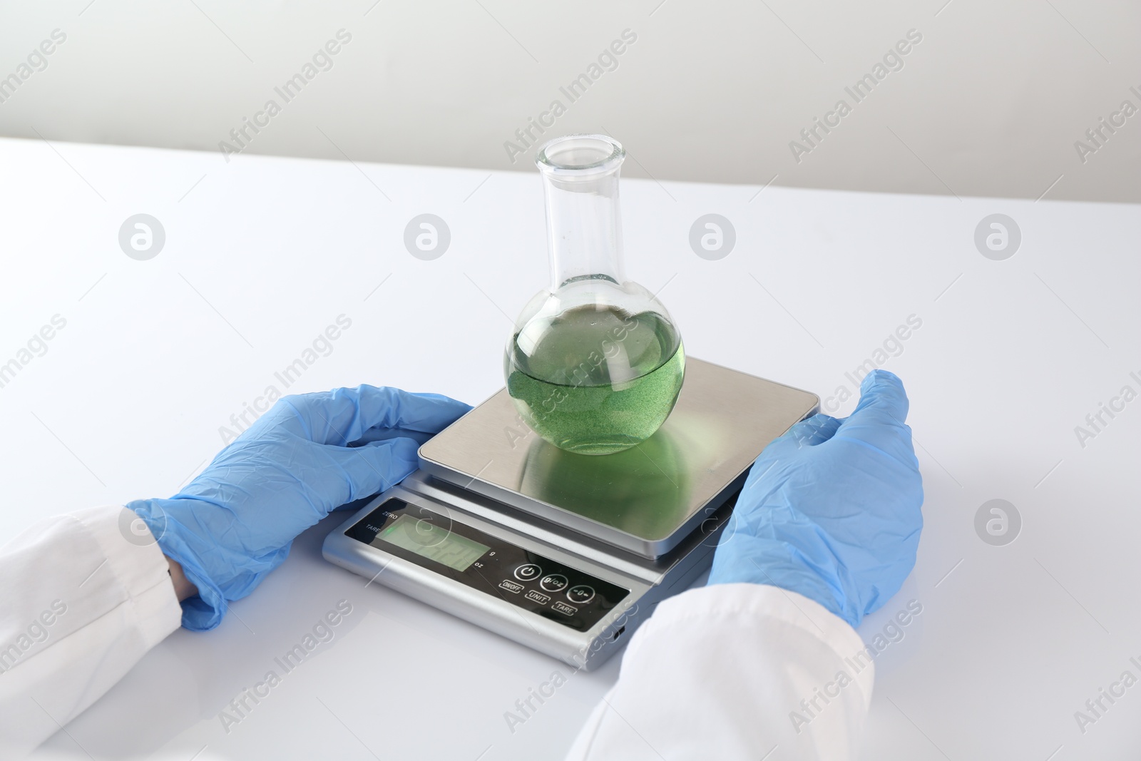 Scientist weighing sample on scales at white table, closeup Photo of Scientist weighing sample on scales at white table, closeup