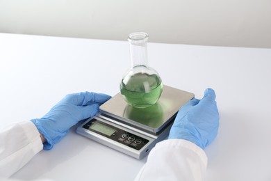 Photo of Scientist weighing sample on scales at white table, closeup