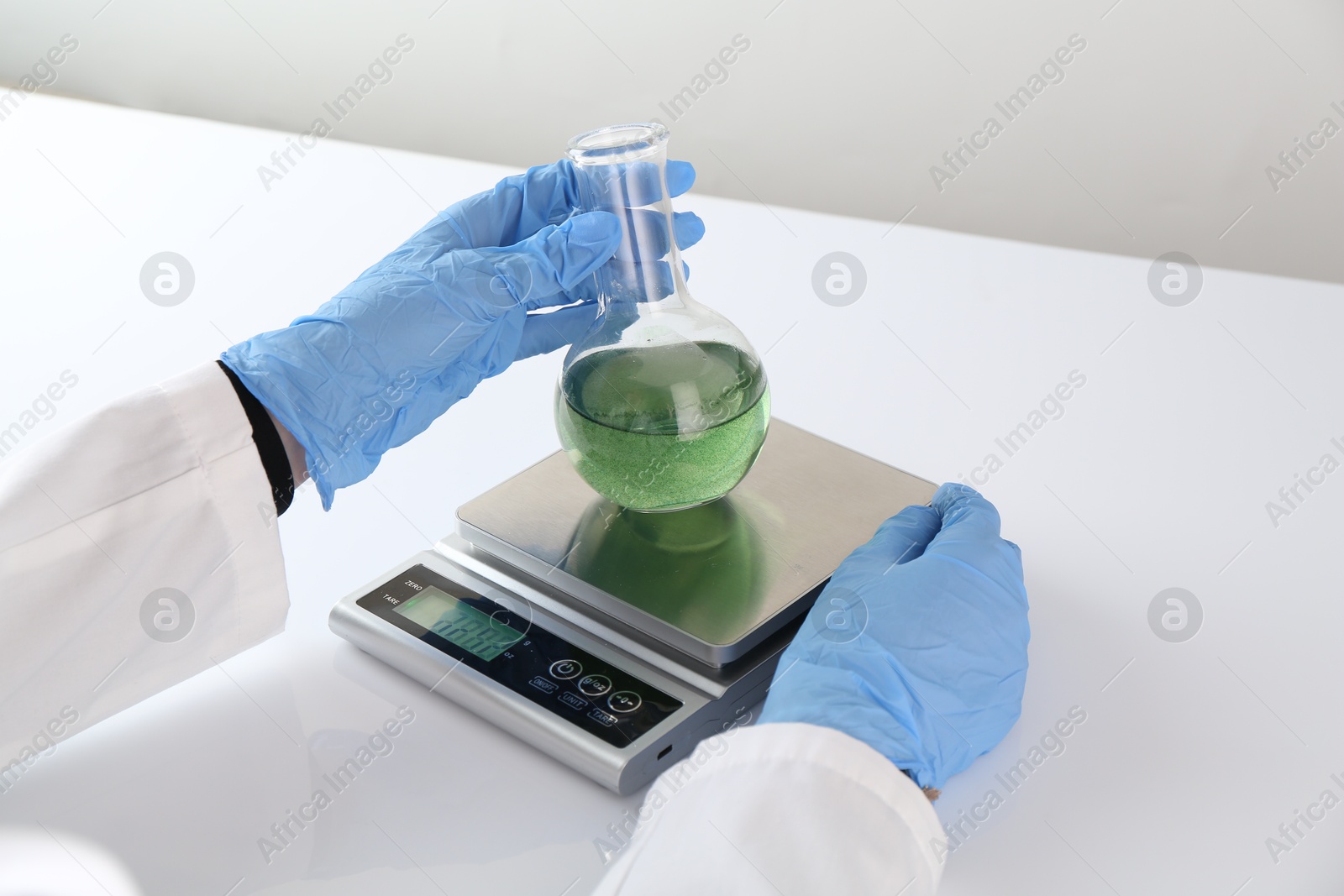 Scientist weighing sample on scales at white table, closeup Photo of Scientist weighing sample on scales at white table, closeup