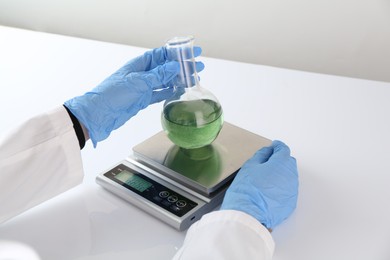 Photo of Scientist weighing sample on scales at white table, closeup