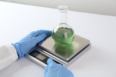Photo of Scientist weighing sample on scales at white table, closeup