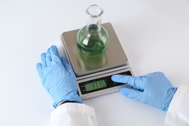 Photo of Scientist weighing sample on scales at white table, closeup