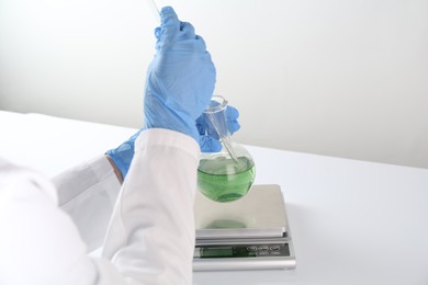 Photo of Scientist working with sample and scales at white table, closeup