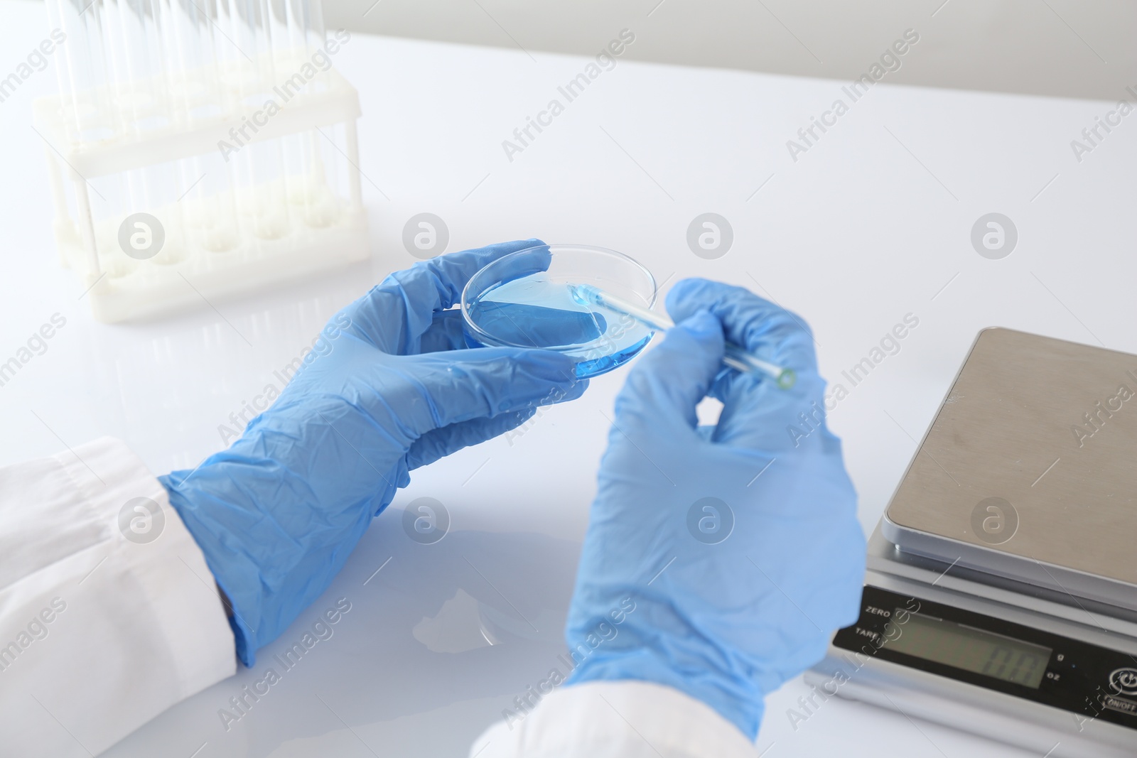 Scientist working with sample near scales at white table, closeup Photo of Scientist working with sample near scales at white table, closeup