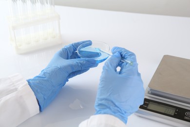 Photo of Scientist working with sample near scales at white table, closeup