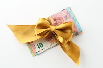Photo of Money bonus. Euro banknotes with bow on white background, top view