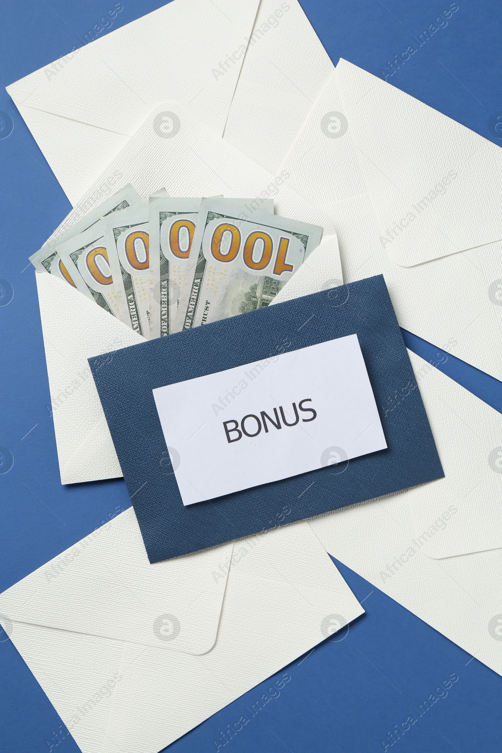 Envelopes with word Bonus and money on blue background, flat lay Photo of Envelopes with word Bonus and money on blue background, flat lay