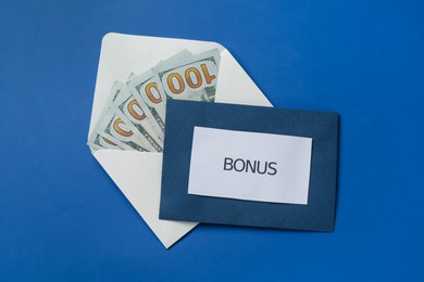 Photo of Envelopes with word Bonus and money on blue background, top view