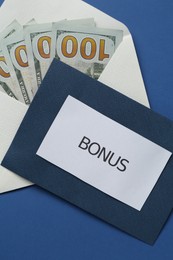 Photo of Envelopes with word Bonus and money on blue background, top view