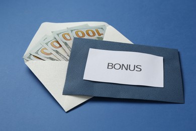 Photo of Envelopes with word Bonus and money on blue background, closeup
