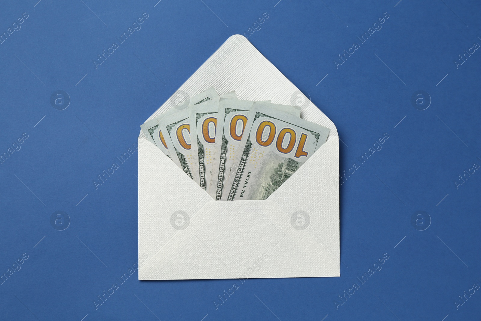 Money bonus. Envelope with dollar banknotes on blue background, top view Photo of Money bonus. Envelope with dollar banknotes on blue background, top view