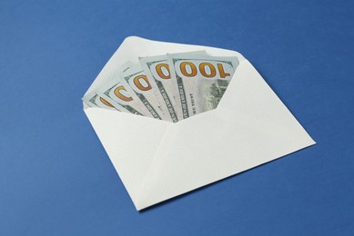 Photo of Money bonus. Envelope with dollar banknotes on blue background