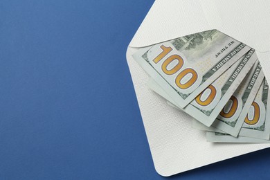 Photo of Money bonus. Envelope with dollar banknotes on blue background, closeup. Space for text