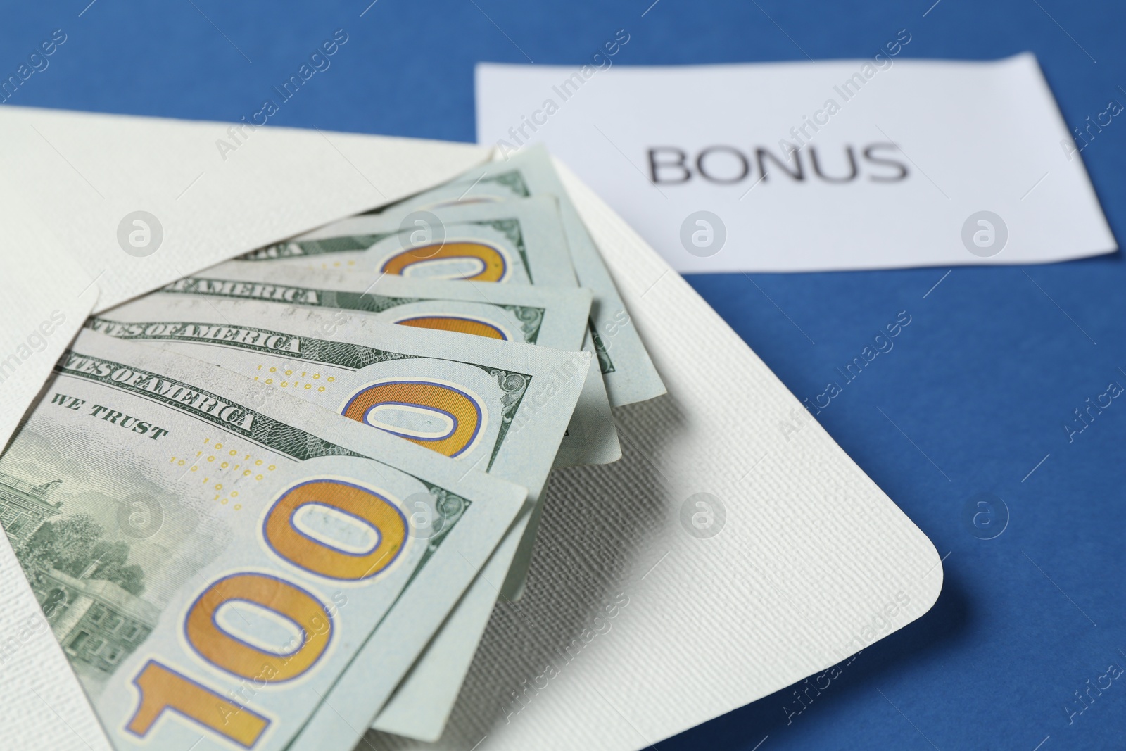 Envelope with money and word Bonus on blue background, closeup Photo of Envelope with money and word Bonus on blue background, closeup