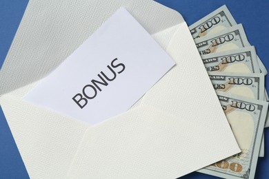 Photo of Envelope with money and word Bonus on blue background, top view
