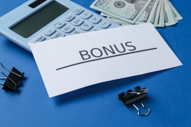 Photo of Card with word Bonus, money, calculator and clips on blue background, closeup