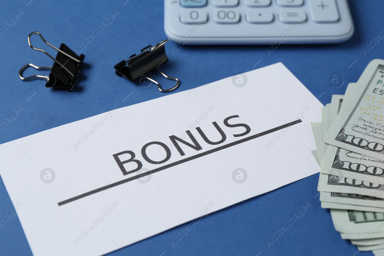 Card with word Bonus, money, calculator and clips on blue background, closeup Photo of Card with word Bonus, money, calculator and clips on blue background, closeup