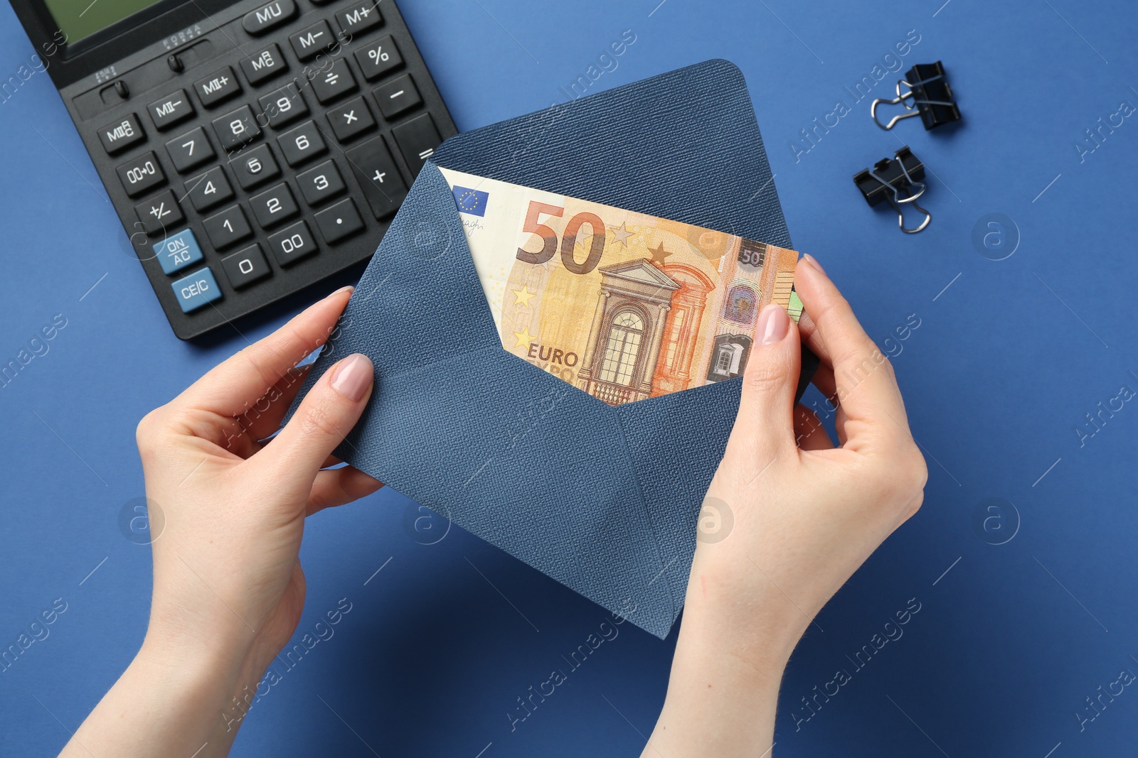 Money bonus. Woman holding envelope with euro banknotes on blue background, closeup Photo of Money bonus. Woman holding envelope with euro banknotes on blue background, closeup