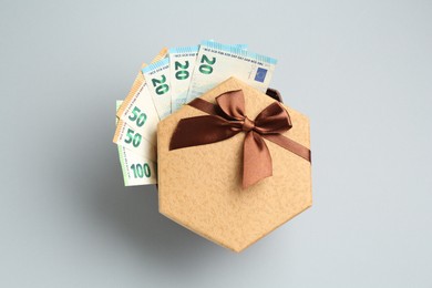 Photo of Money bonus. Gift box with euro banknotes on light grey background, top view
