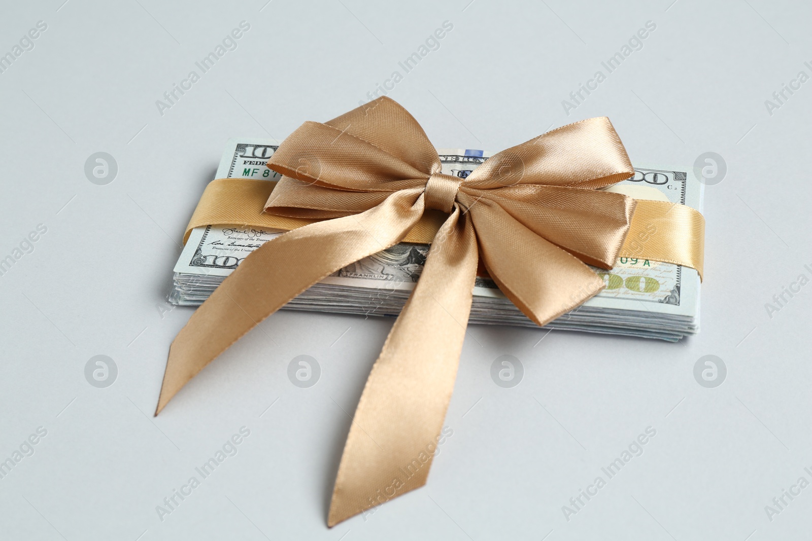 Money bonus. Dollar banknotes with bow on light grey background, closeup Photo of Money bonus. Dollar banknotes with bow on light grey background, closeup