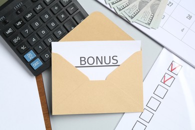 Photo of Envelope with word Bonus, money, calculator and paperwork on light grey background, flat lay