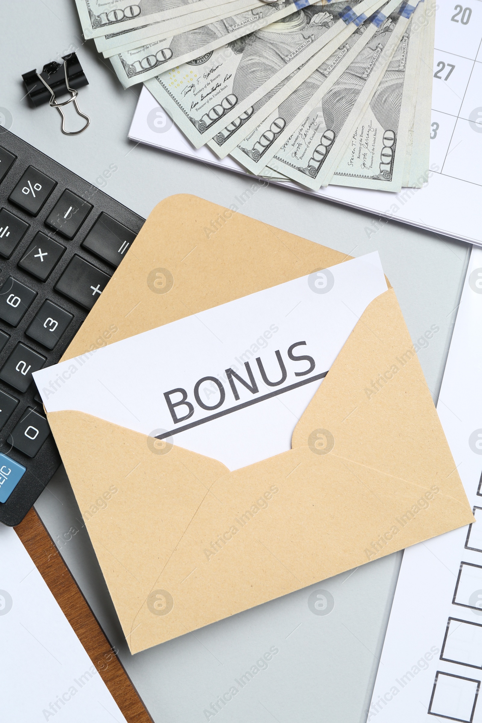 Envelope with word Bonus, money, calculator and paperwork on light grey background, flat lay Photo of Envelope with word Bonus, money, calculator and paperwork on light grey background, flat lay