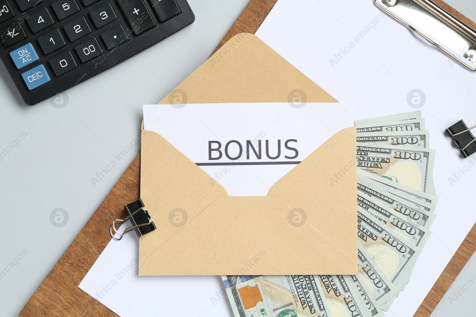 Envelope with word Bonus, money, calculator and paperwork on light grey background, flat lay Photo of Envelope with word Bonus, money, calculator and paperwork on light grey background, flat lay