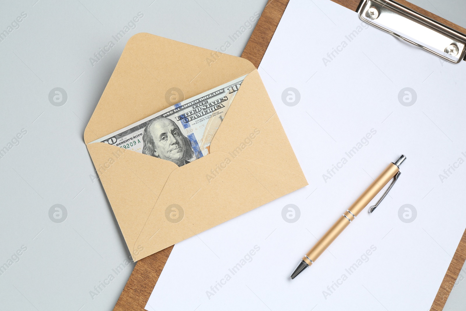 Money bonus. Envelope with dollar banknotes and clipboard on light grey background, top view Photo of Money bonus. Envelope with dollar banknotes and clipboard on light grey background, top view