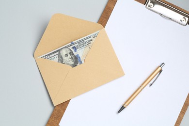 Photo of Money bonus. Envelope with dollar banknotes and clipboard on light grey background, top view