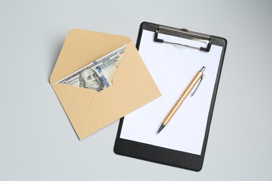 Photo of Money bonus. Envelope with dollar banknotes and clipboard on light grey background, top view