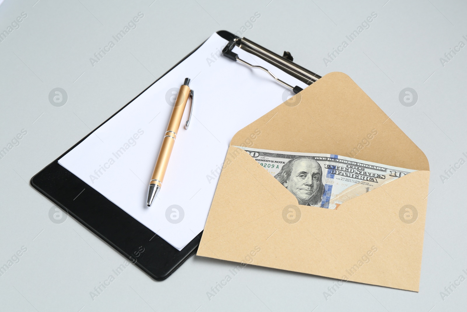 Money bonus. Envelope with dollar banknotes and clipboard on light grey background, closeup Photo of Money bonus. Envelope with dollar banknotes and clipboard on light grey background, closeup