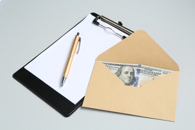Photo of Money bonus. Envelope with dollar banknotes and clipboard on light grey background, closeup