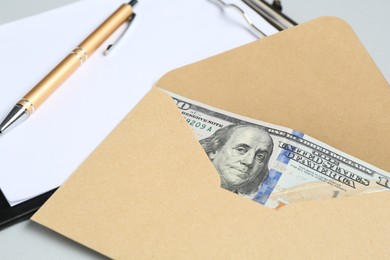 Photo of Money bonus. Envelope with dollar banknotes and clipboard on light grey background, closeup