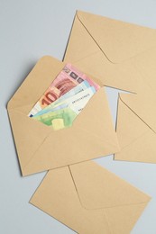 Photo of Money bonus. Envelopes with euro banknotes on light grey background, flat lay
