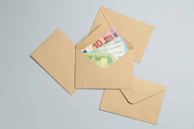 Photo of Money bonus. Envelopes with euro banknotes on light grey background, flat lay