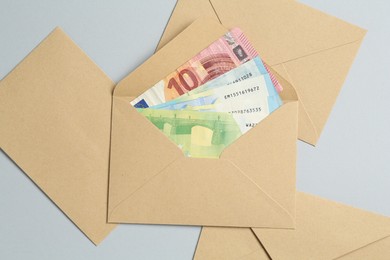 Photo of Money bonus. Envelopes with euro banknotes on light grey background, flat lay