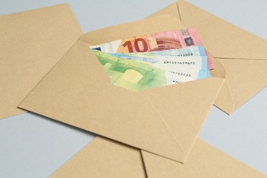 Photo of Money bonus. Envelopes with euro banknotes on light grey background, closeup