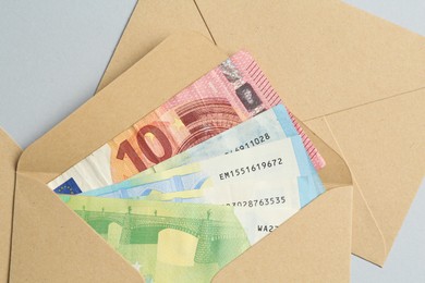 Photo of Money bonus. Envelopes with euro banknotes on light grey background, closeup