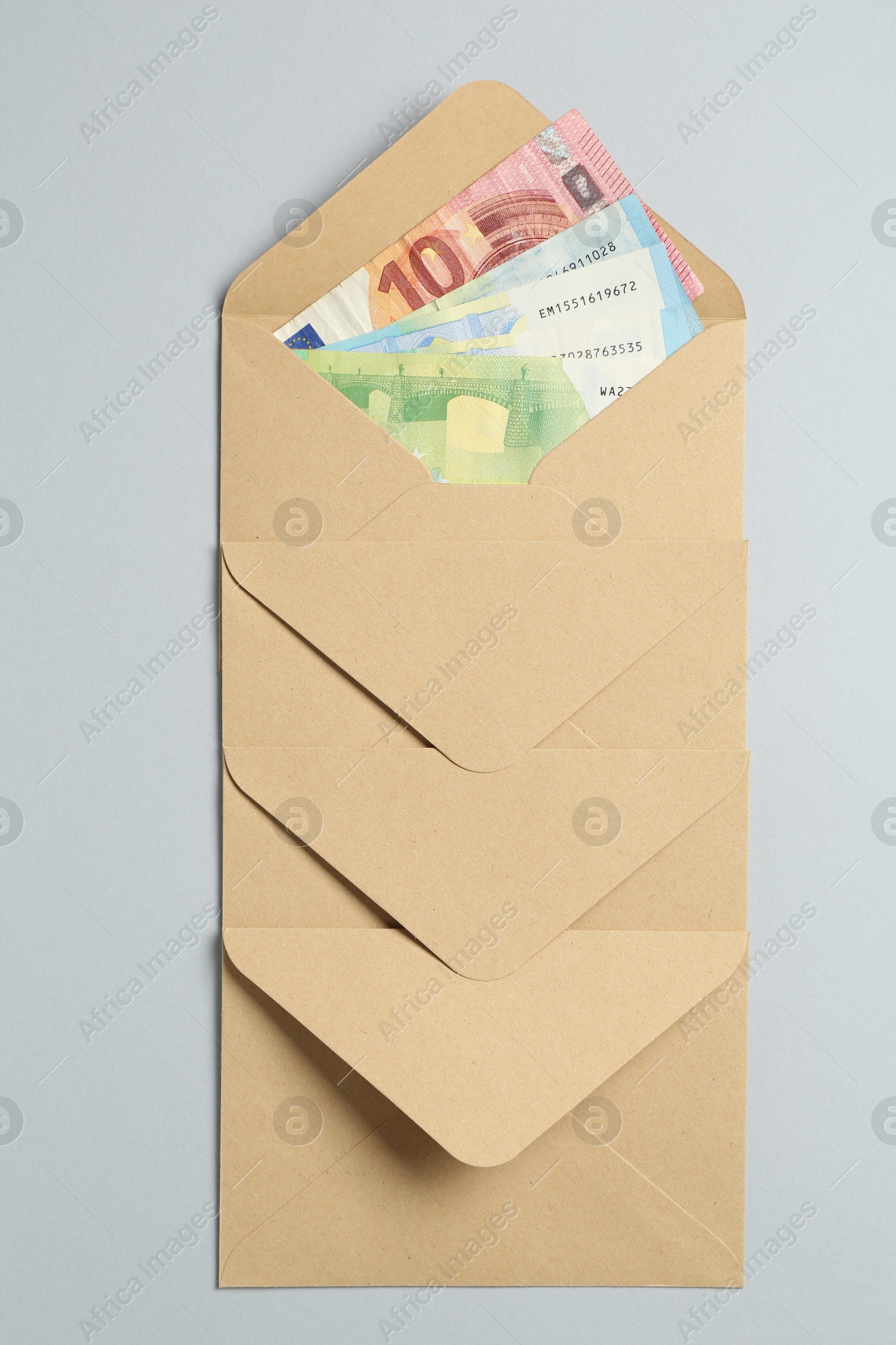 Money bonus. Envelopes with euro banknotes on light grey background, top view Photo of Money bonus. Envelopes with euro banknotes on light grey background, top view