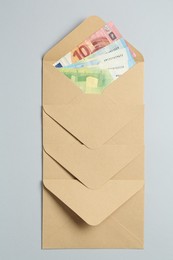 Photo of Money bonus. Envelopes with euro banknotes on light grey background, top view
