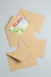Photo of Money bonus. Envelopes with euro banknotes on light grey background, flat lay