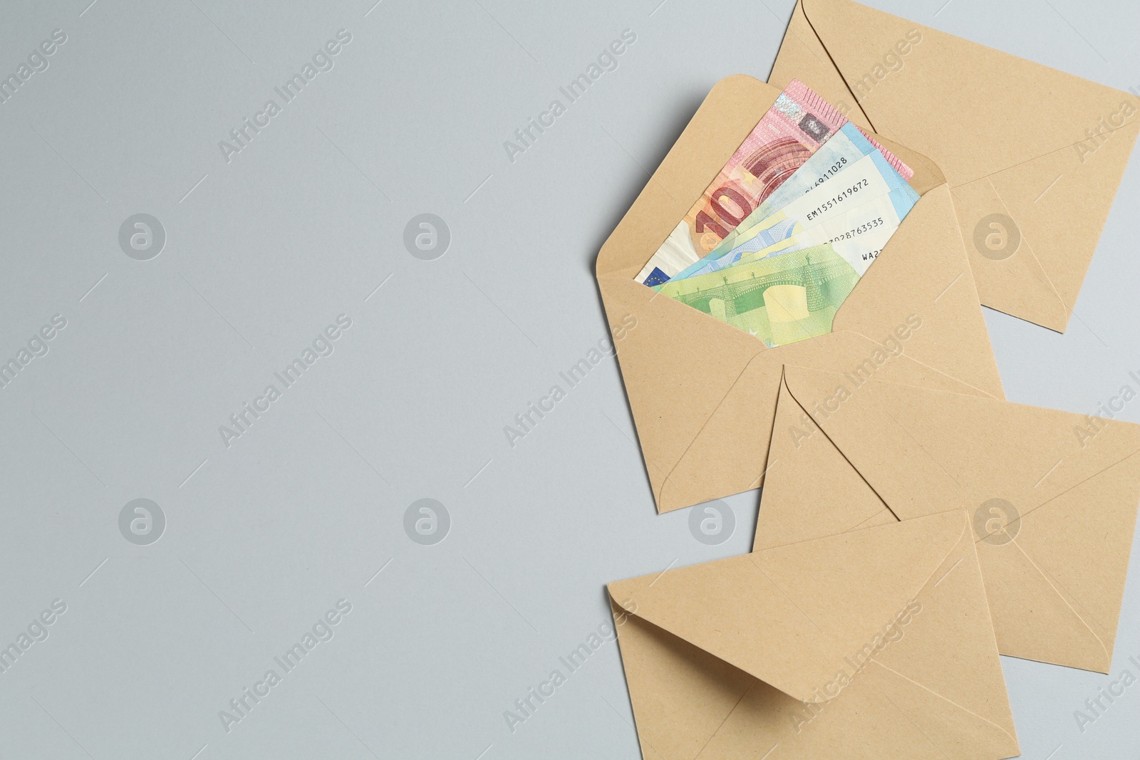 Money bonus. Envelopes with euro banknotes on light grey background, flat lay. Space for text Photo of Money bonus. Envelopes with euro banknotes on light grey background, flat lay. Space for text
