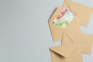 Photo of Money bonus. Envelopes with euro banknotes on light grey background, flat lay. Space for text